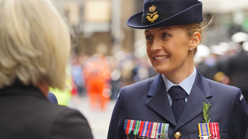 A blonde woman dons her medals and wears her RAAF uniform