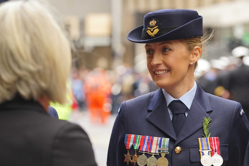 A blonde woman dons her medals and wears her RAAF uniform