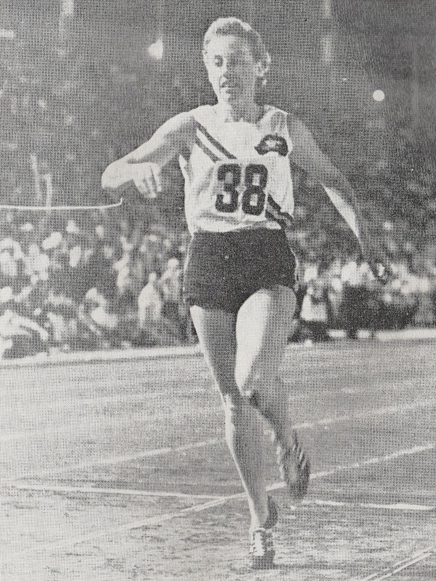 A black and white image of Judy Amoore Pollock crossing the finish line in the 800 metres.