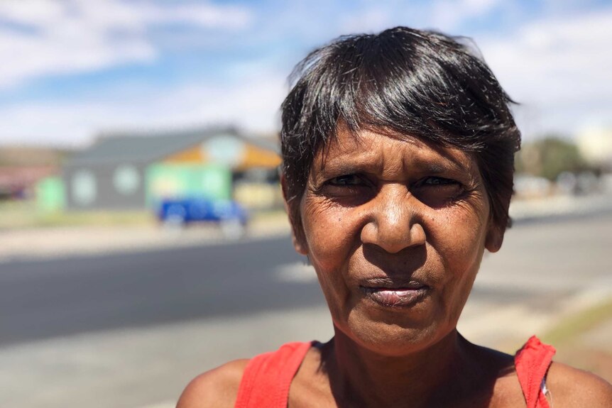 A head shot of Indigenous woman Julie Bugmy, with Argent Street in soft focus behind her.