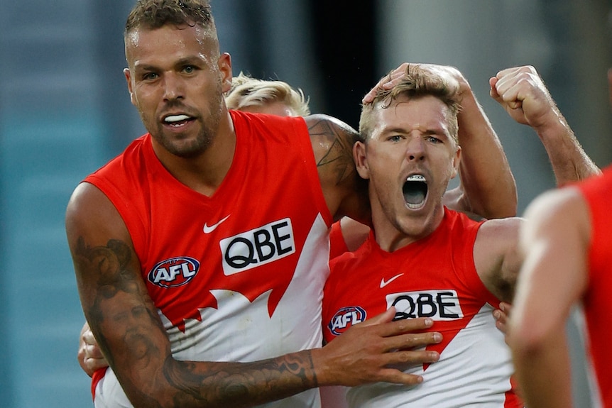 Lance Franklin hugs Luke Parker as he clenches his fist and yells