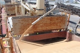 grain pours into a large  compartment of a big bulk carrier vessel