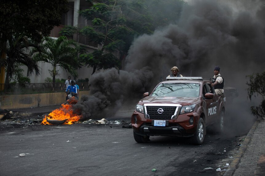 Police drive their car over a barricade set up by taxi drivers to protest fuel shortages in Port-au-Prince.