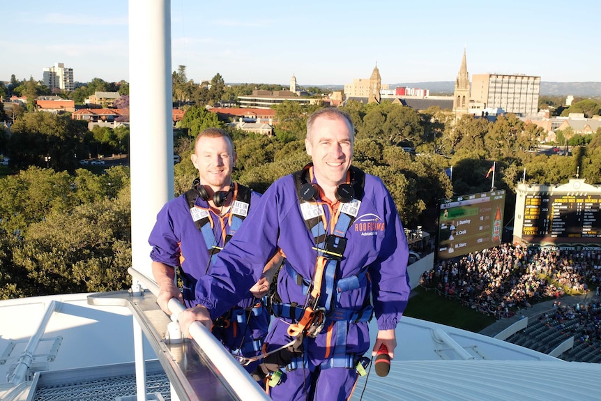 Gerard Whateley and Chris Rogers make their way up Adelaide Oval roof