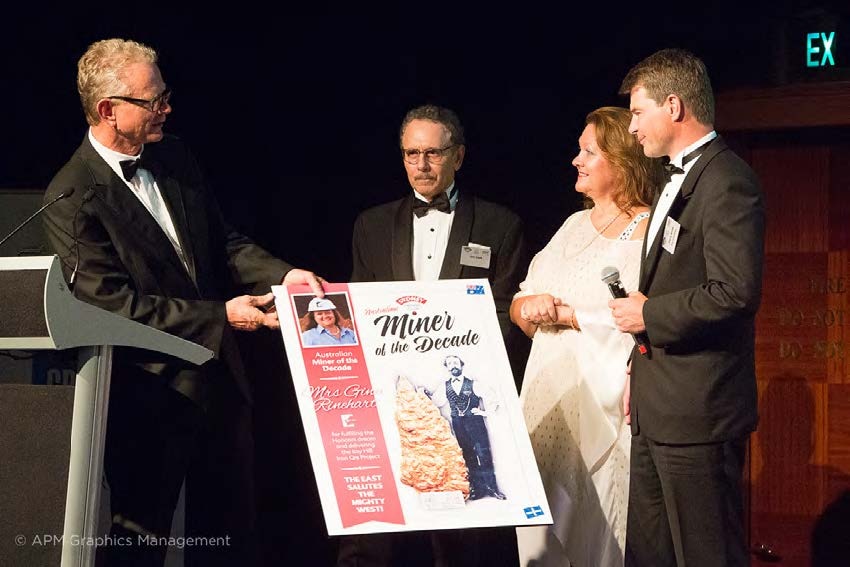 Julian Malnic presents Gina Rinehart a novelty sized award certificate while two men watch on.