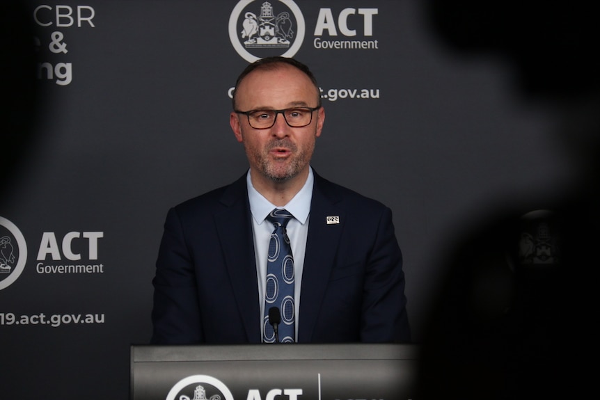 ACT Chief Minister Andrew Barr speaks in front of a podium.