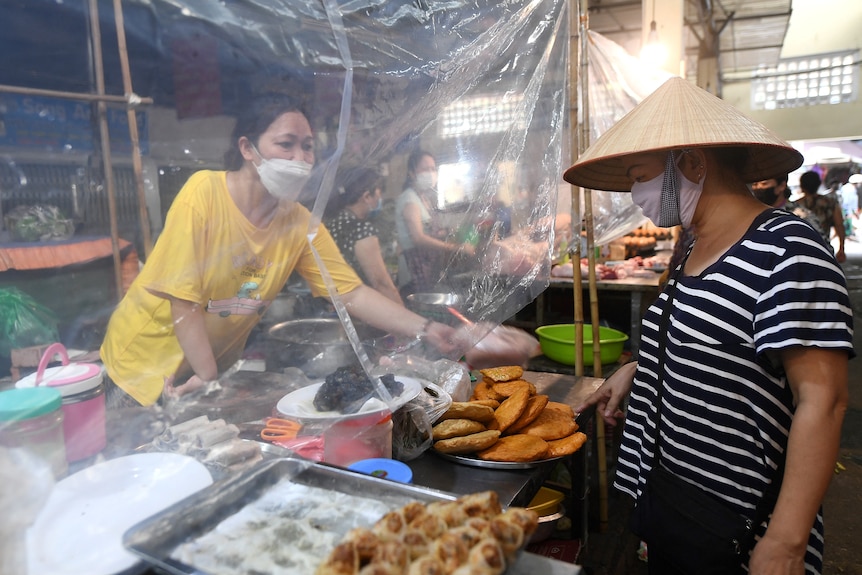 A vendor sells delicacies from behind a plastic sheet at a local market in Hanoi 