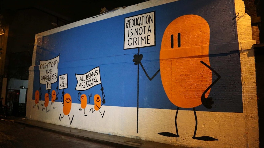 Various orange beans hold signs up referencing education not being a crime.