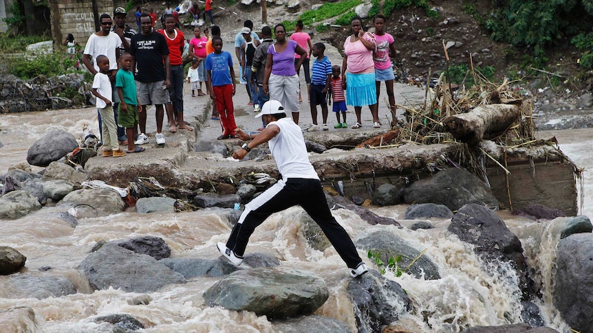People in Kingston, Jamaica try to cross the Hope River after a bridge was washed out by Hurricane Sandy, on October 25, 2012.