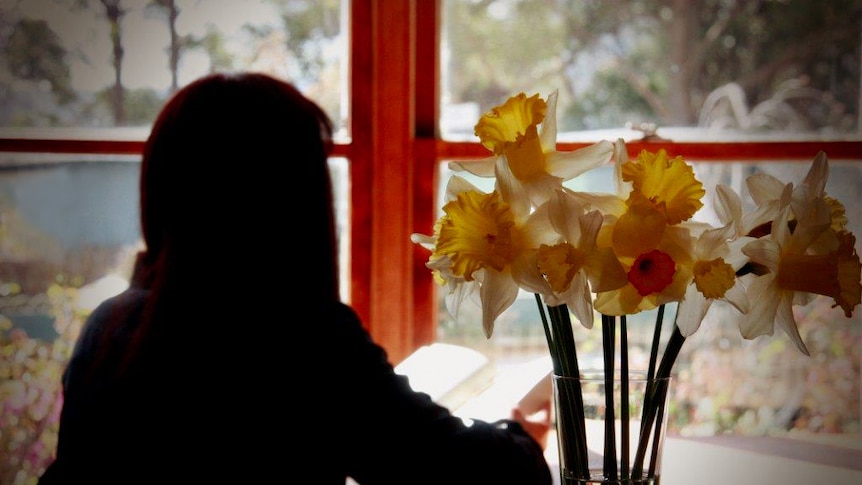 A woman in silhouette with daffodils in the foreground.