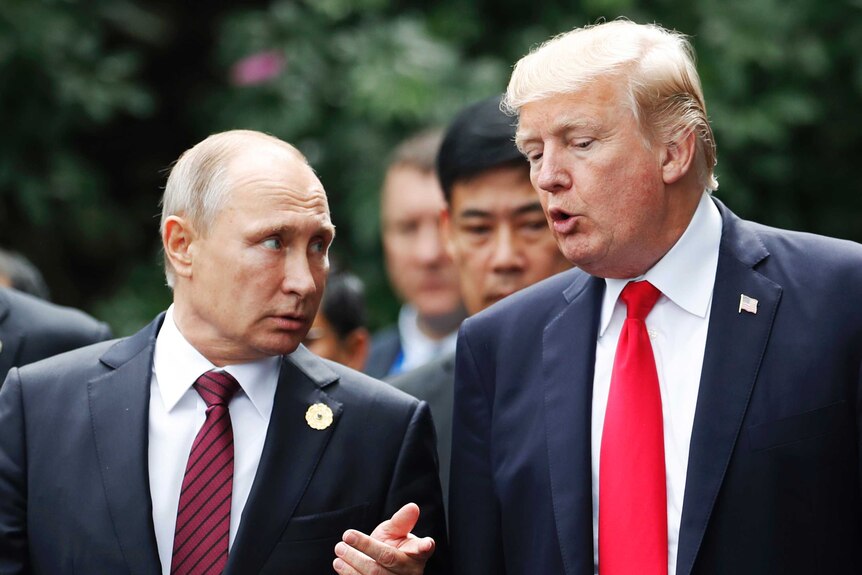 Donald Trump speaks to Vladimir Putin standing next to him.