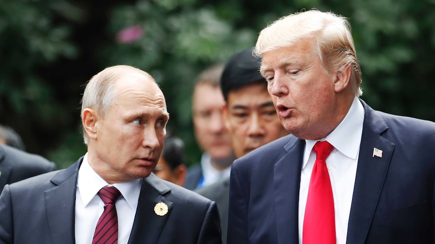 Donald Trump speaks to Vladimir Putin standing next to him.