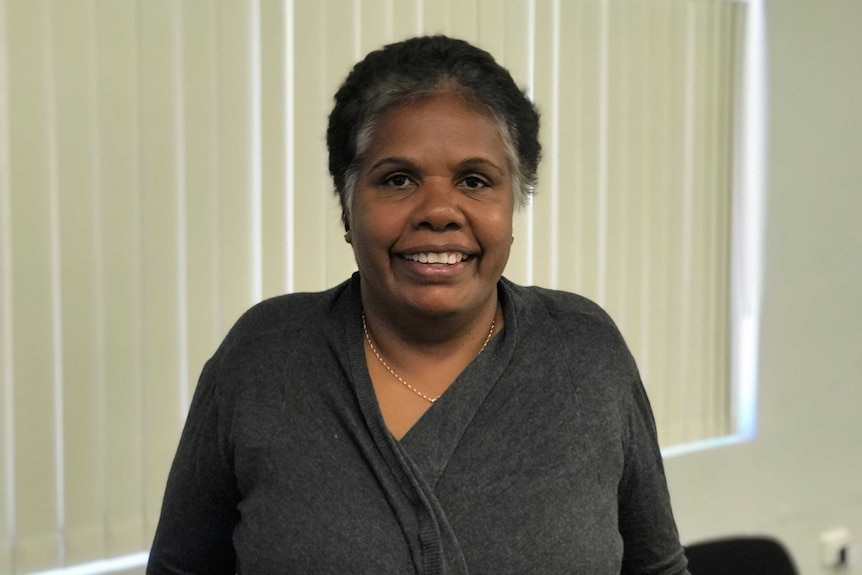 A woman with dark skin and short black hair, smiling.