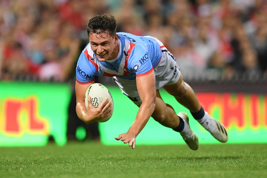 A Sydney Roosters NRL player dives in the air as he holds the ball before scoring a try.