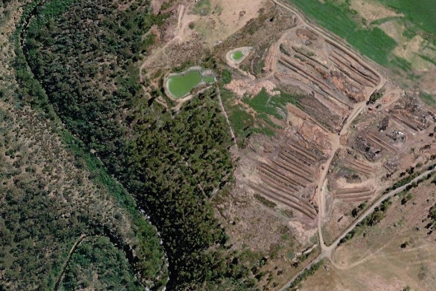 An aerial view of an industrial dump/compost site next to a river.
