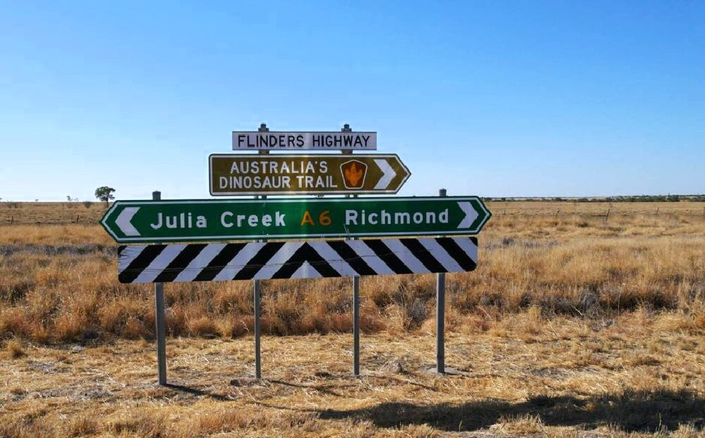 A highway sign with 'Julia Creek' in one direction and 'Richmond' in the other.