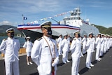 Taiwanese Navy personnel wear white uniforms while standing in front of a new ship