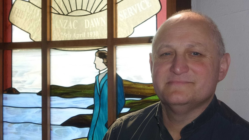 Father Edward Argyle in front of the church's Padre White memorial window