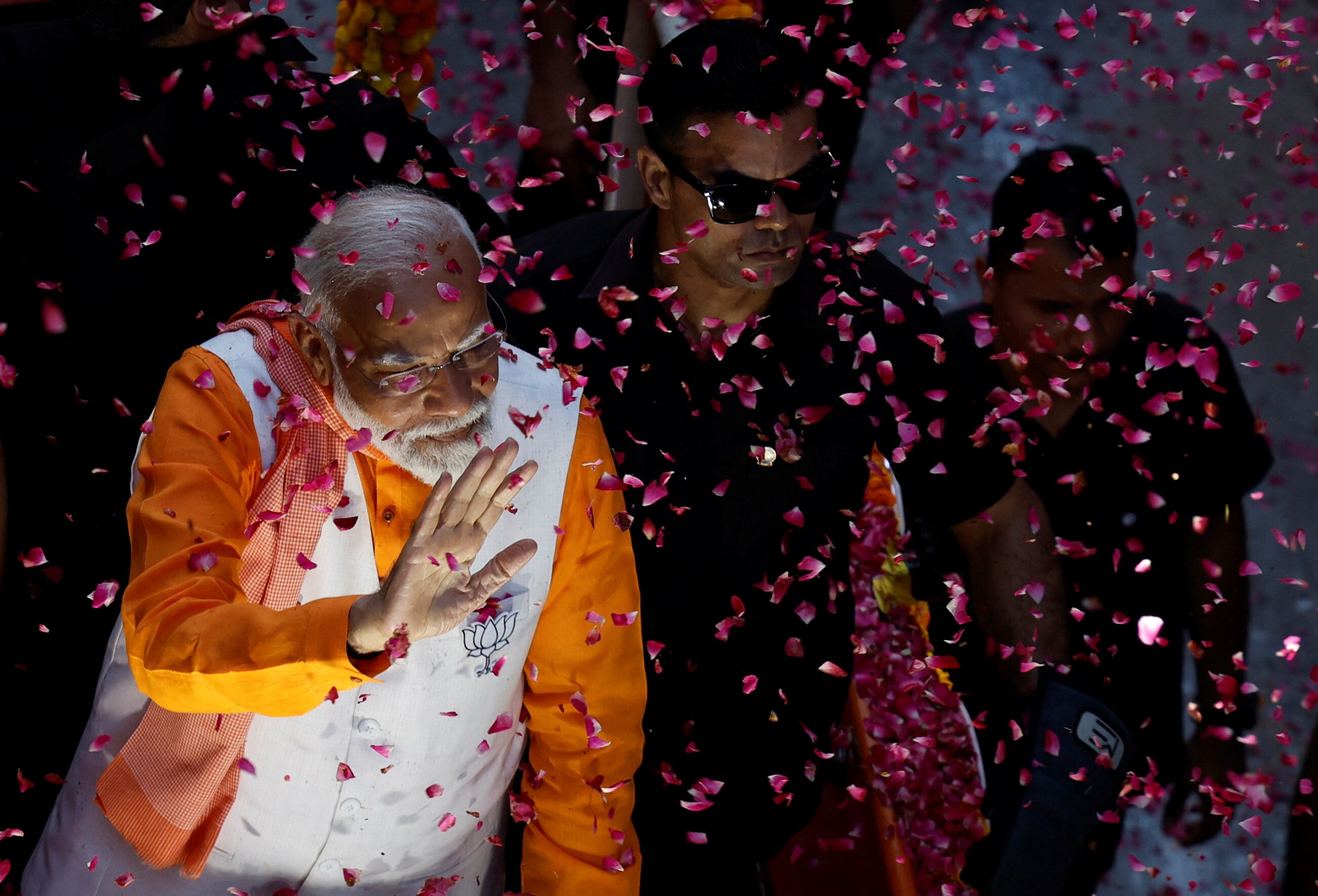 A man waves as rose petals fall around him 