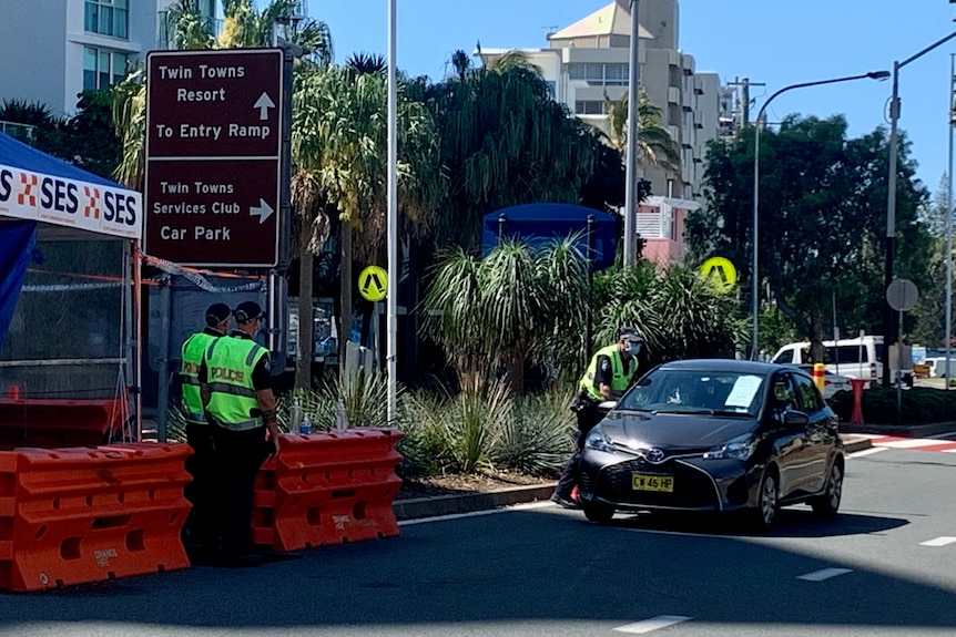 Police at a checkpoint investigating a car.