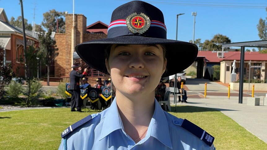 A female cadet is dressed in formal parade uniform, smiling happily.