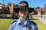 A female cadet is dressed in formal parade uniform, smiling happily.