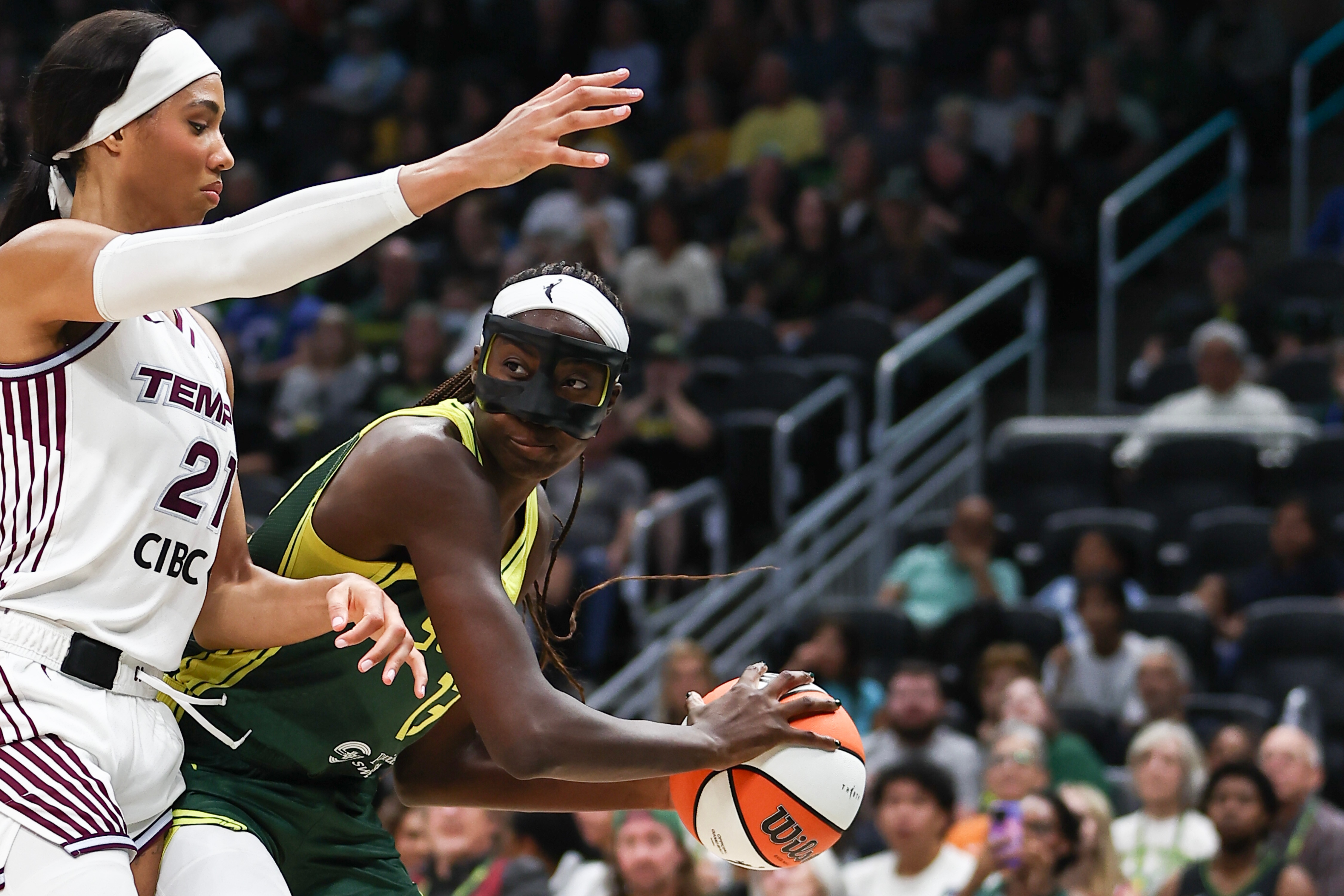 Basketballer Ezi Magbegor, wearing a black protective face mask, looks to pass the ball during a game