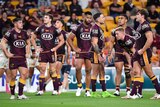 A group of NRL teammates stand looking dejected after a try by their opposing team in a game.