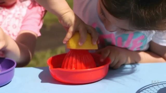 Child's hand squeezes half a lemon on a juicer