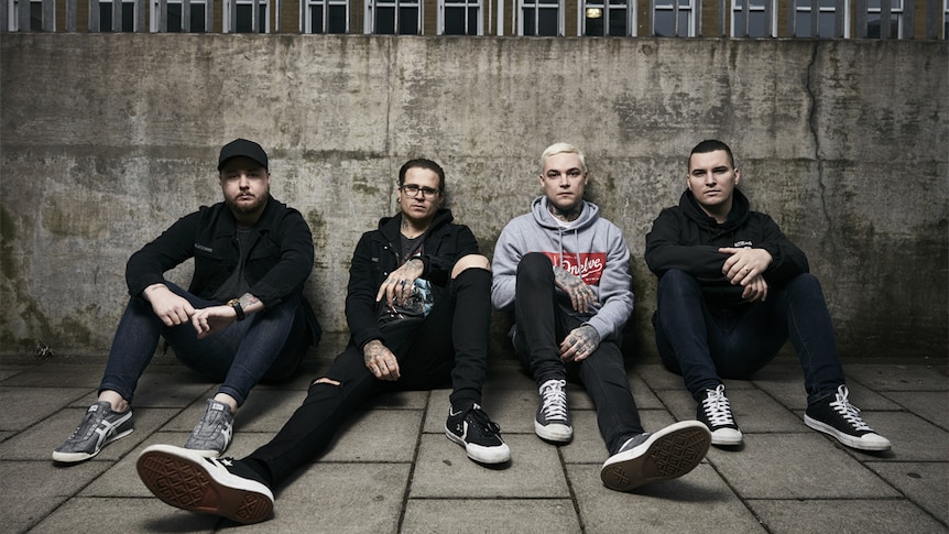 A 2016 press shot of The Amity Affliction sitting against a concrete wall