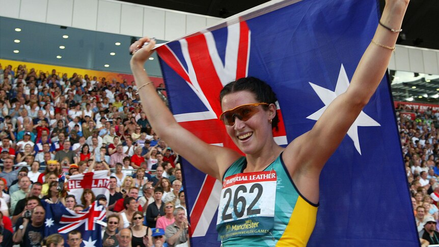 Australian athlete smiles holding high an Australian flag
