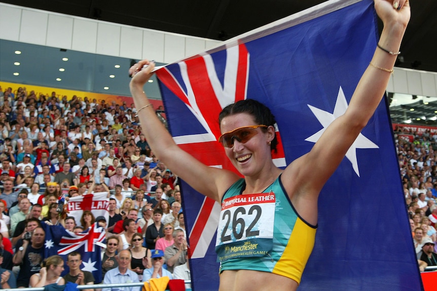 Australian athlete smiles holding high an Australian flag