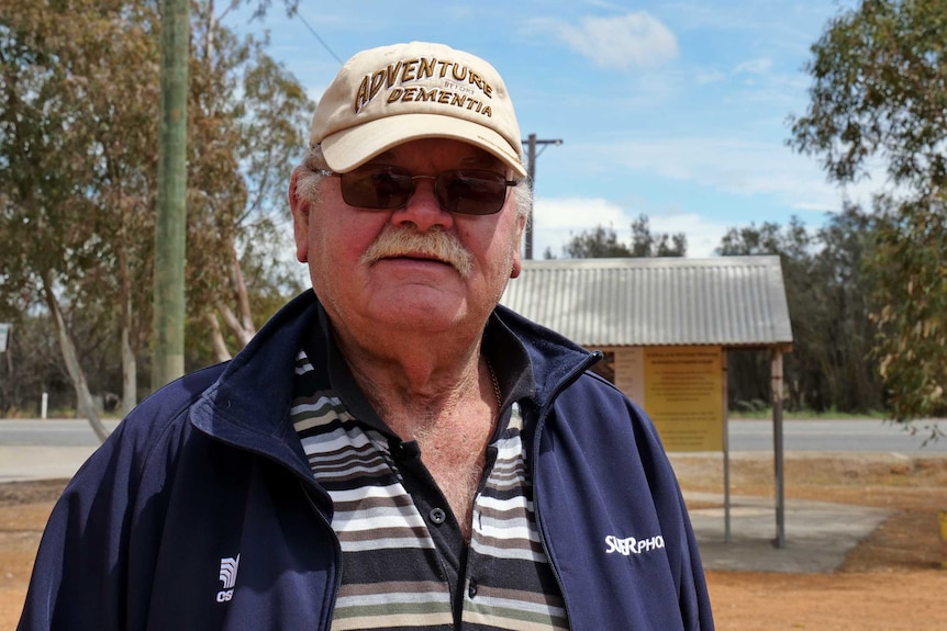 A man wearing a cap looks at the camera