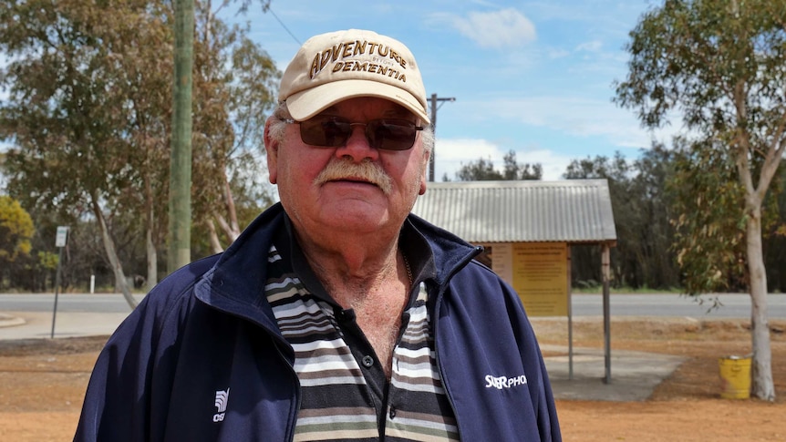 A man wearing a cap looks at the camera