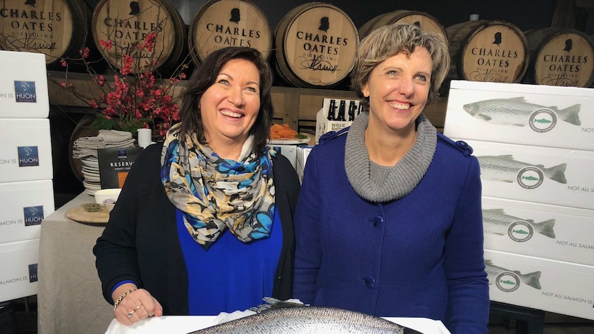Huon Aquaculture's Frances Bender and RSPCA Australia CEO Heather Neil stand, smiling, in front of a dead fish.