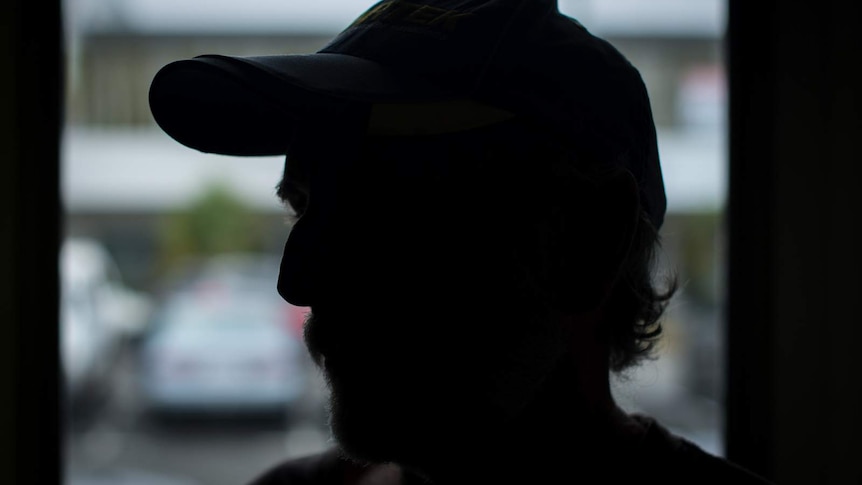 A silhouetted picture of 'Tom' standing in front of a window at the Alcohol Tobacco and Other Drugs Service clinic in Cairns.