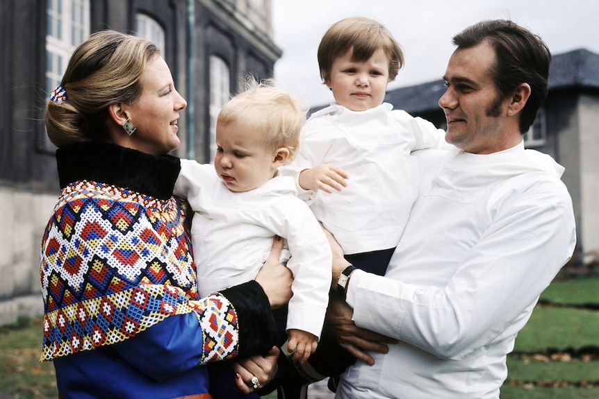 Queen margrethe wearing a patterned jumper and husband Henrik in white polo hold their two young sons