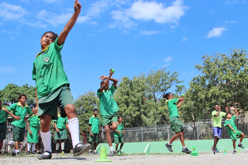 A low angle short of four students bowling the ball simultaneously.