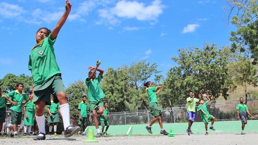 A low angle short of four students bowling the ball simultaneously.