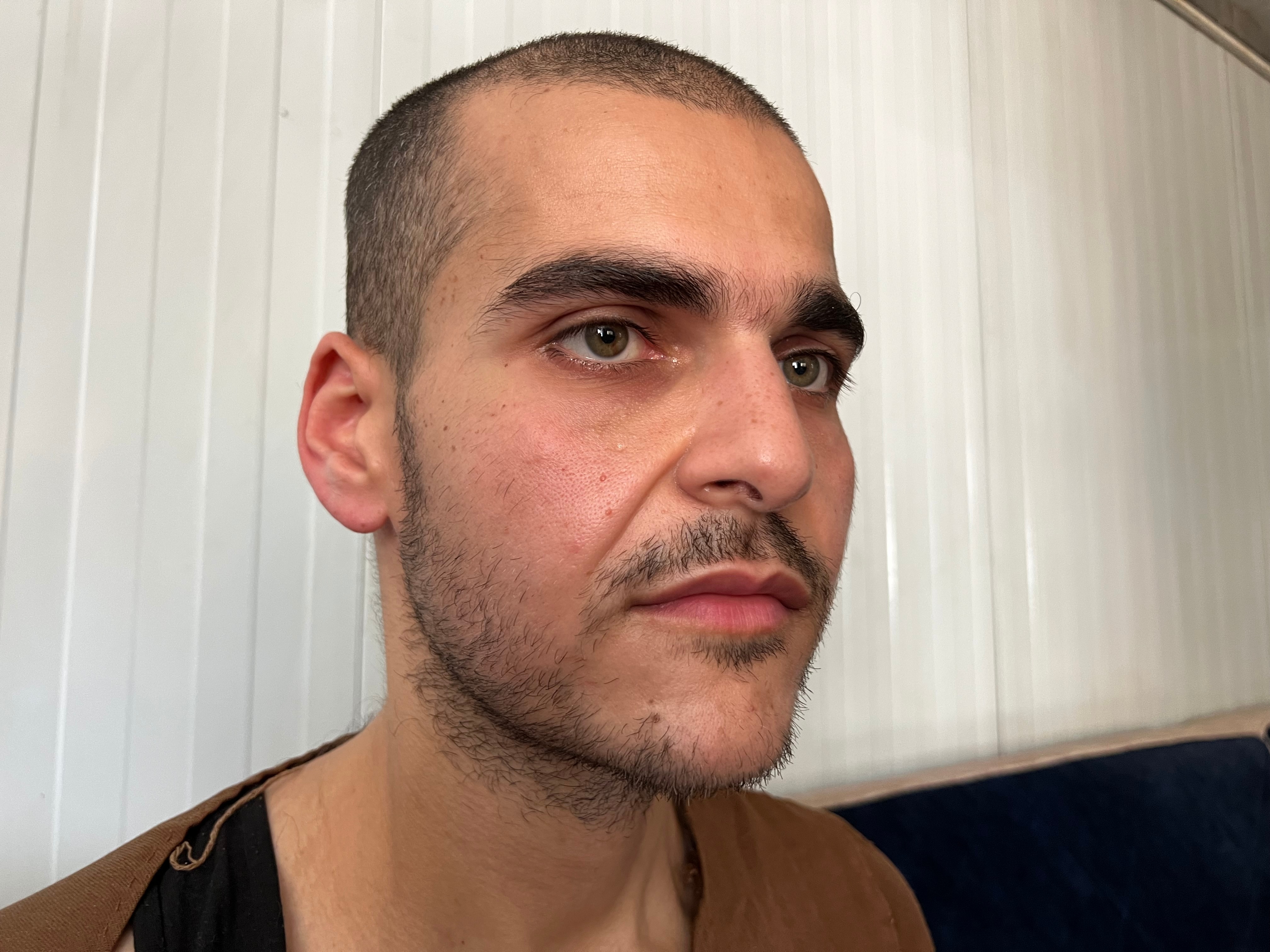 Close up of a young man with a short dark beard and close cropped hair. 