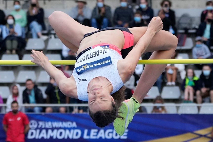 An Australian athlete arches her back as she goes over the bar in a high jump competition.