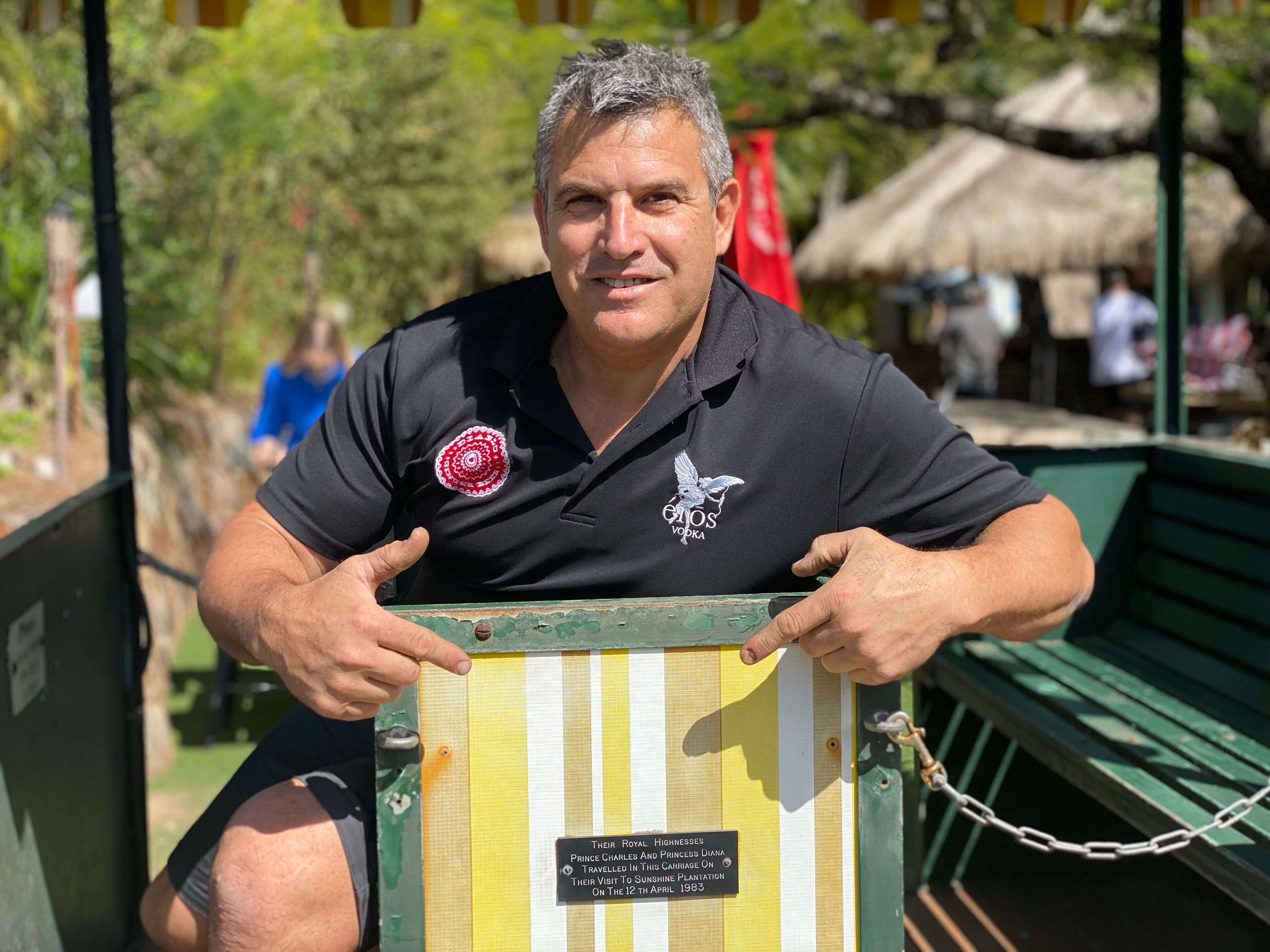 Man on train carriage, pointing at plaque on side