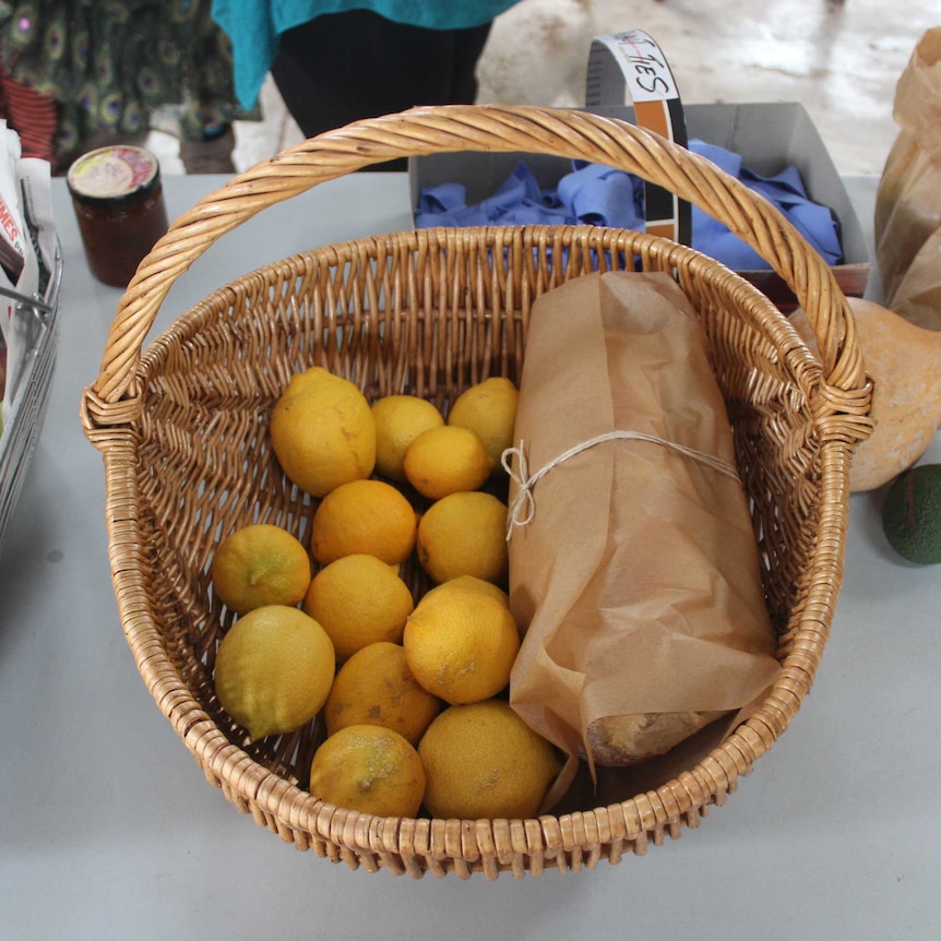 A basket of lemons, bread, and figs on a table.
