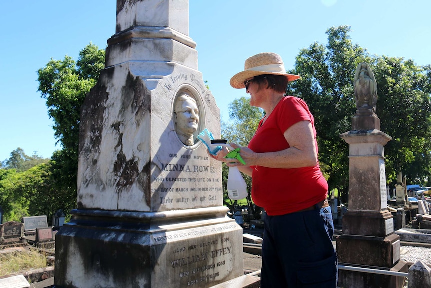 A woman cleans an ornate headstone in the South Brisbane cemetery.