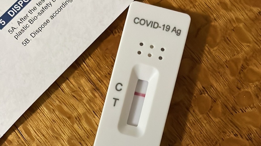 A negative COVID-19 rapid antigen test and the instruction paper sitting on a wooden table 