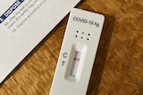 A negative COVID-19 rapid antigen test and the instruction paper sitting on a wooden table 