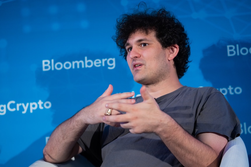 A man gestures in front of a screen that says Bloomberg.