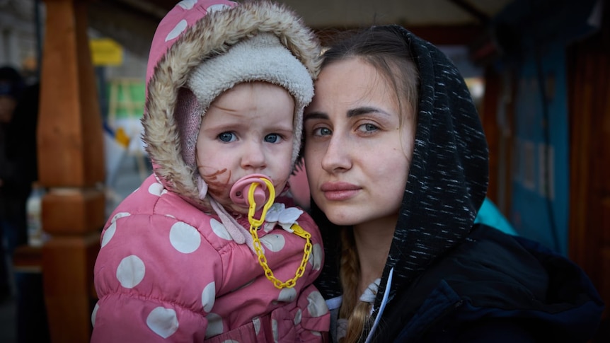 A distraught-looking woman holds a young girl.