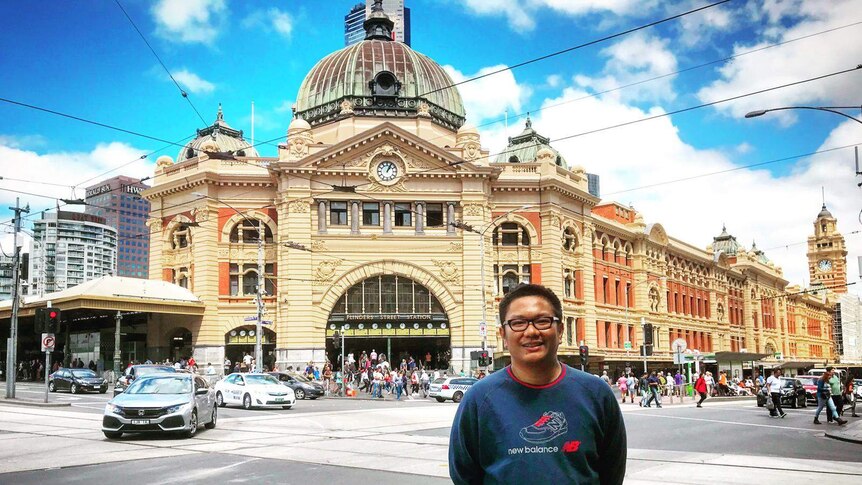 Seorang pria berfoto di depan stasiun kereta Flinders Station