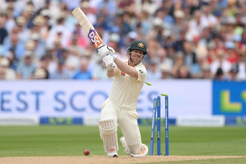 David Warner completes an aggressive shot as the ball breaks the stumps behind him